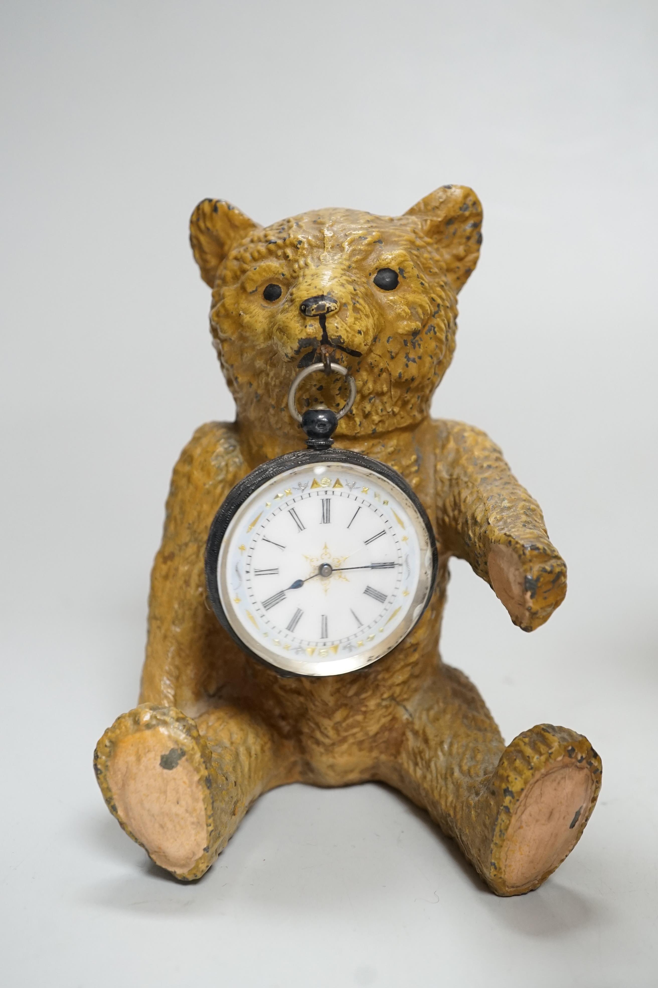 A Smith teddy bear clock, a seated metal bear holding a pocket watch, a metal standing bear with parasol and a German metal bear calendar